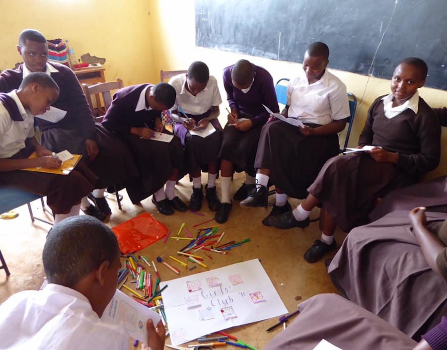 Tanzanian school girls creating a poster board related on Gender Equality