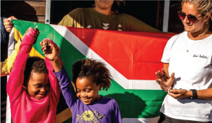 volunteer with local kids and flag of Africa