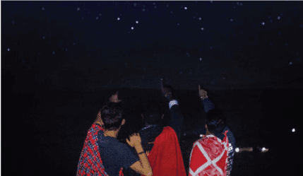 three boys in Africa pointing to the stars