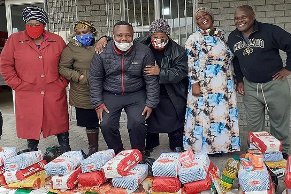 Group of people smiling and standing together in front of donated food