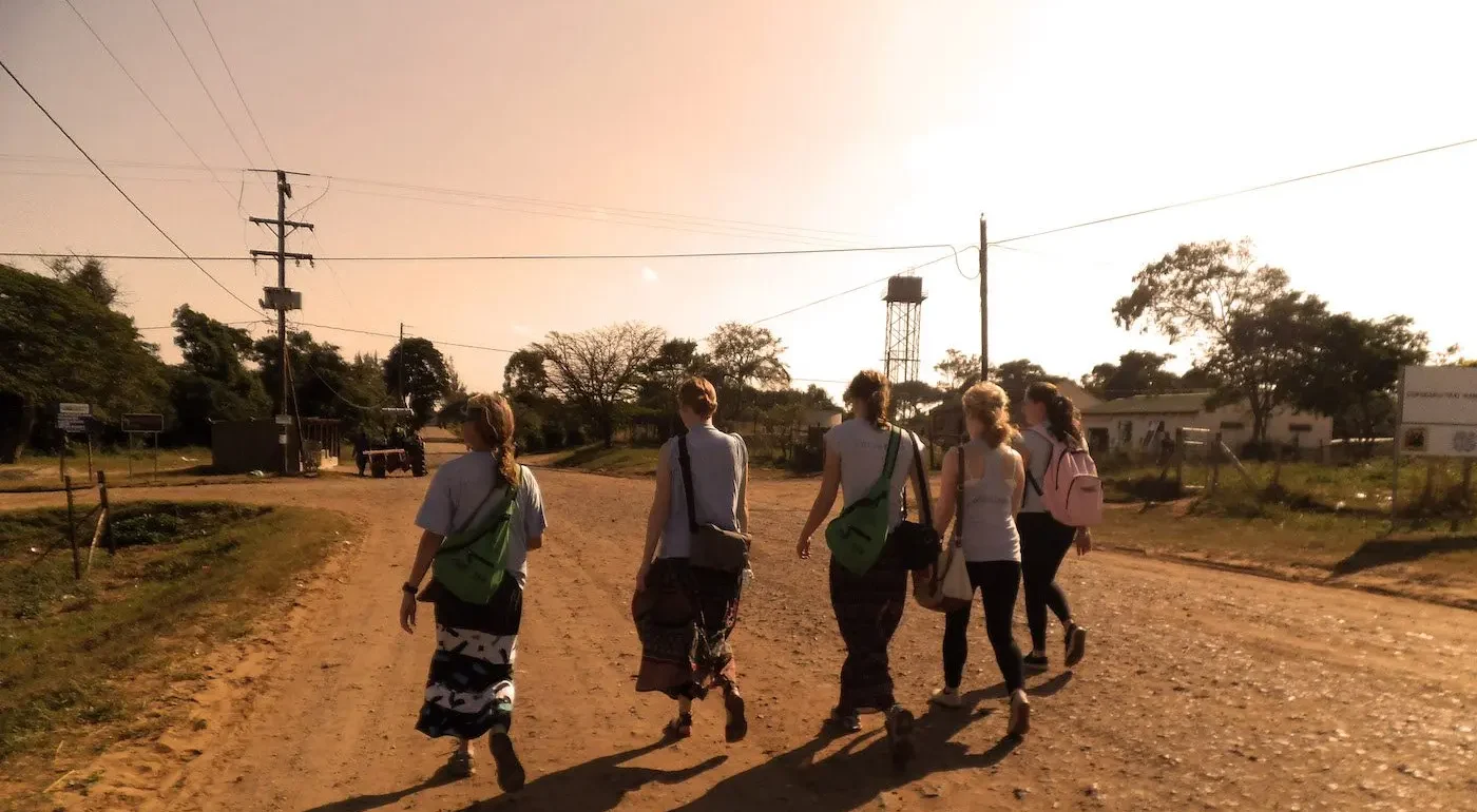 Five female volunteers walk together while on their way to their wildlife and conservation projects.