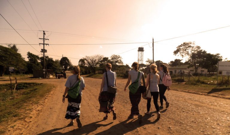 Five female volunteers walk together while on their way to their wildlife and conservation projects.