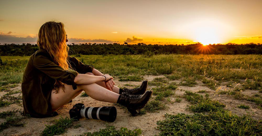Photography volunteer sitting beside her camera, watching the sunrise.
