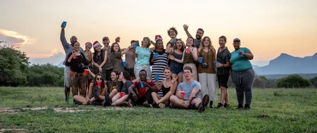 A group of volunteers poses for a group photo against the stunning backdrop of majestic mountains.