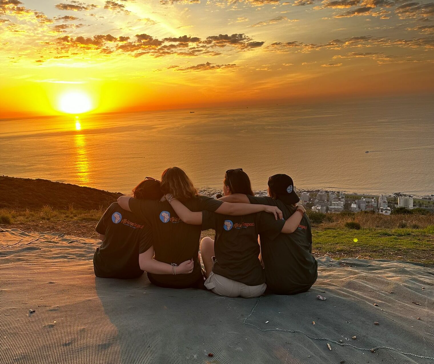 Four volunteers watching the sunset together on Signal hill.