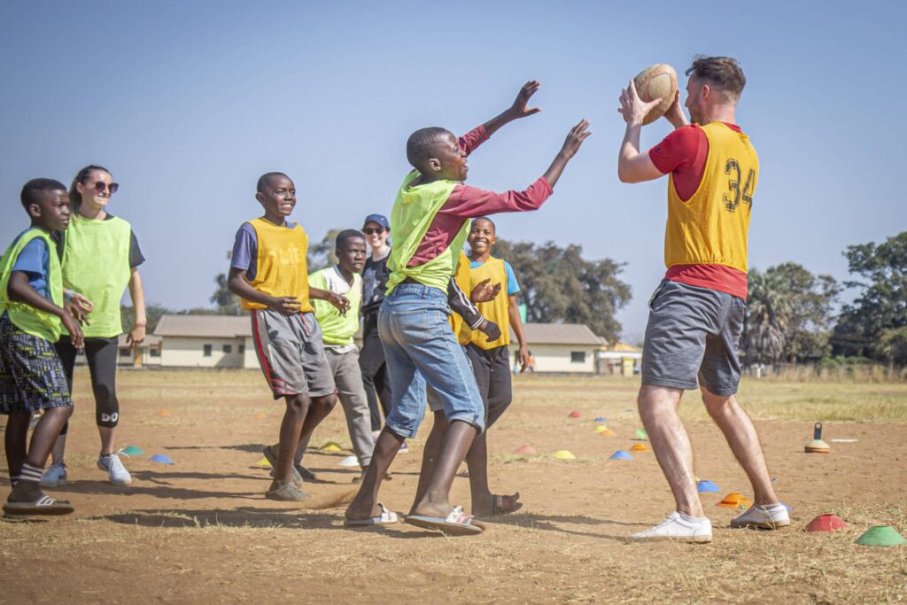 Boys_Rugby-68 Two sports coaching volunteers playing sports with young kids.