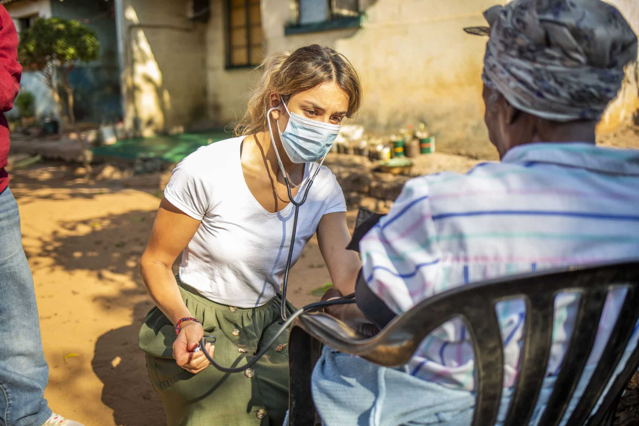 young lady giving a health check to a local zambian woman