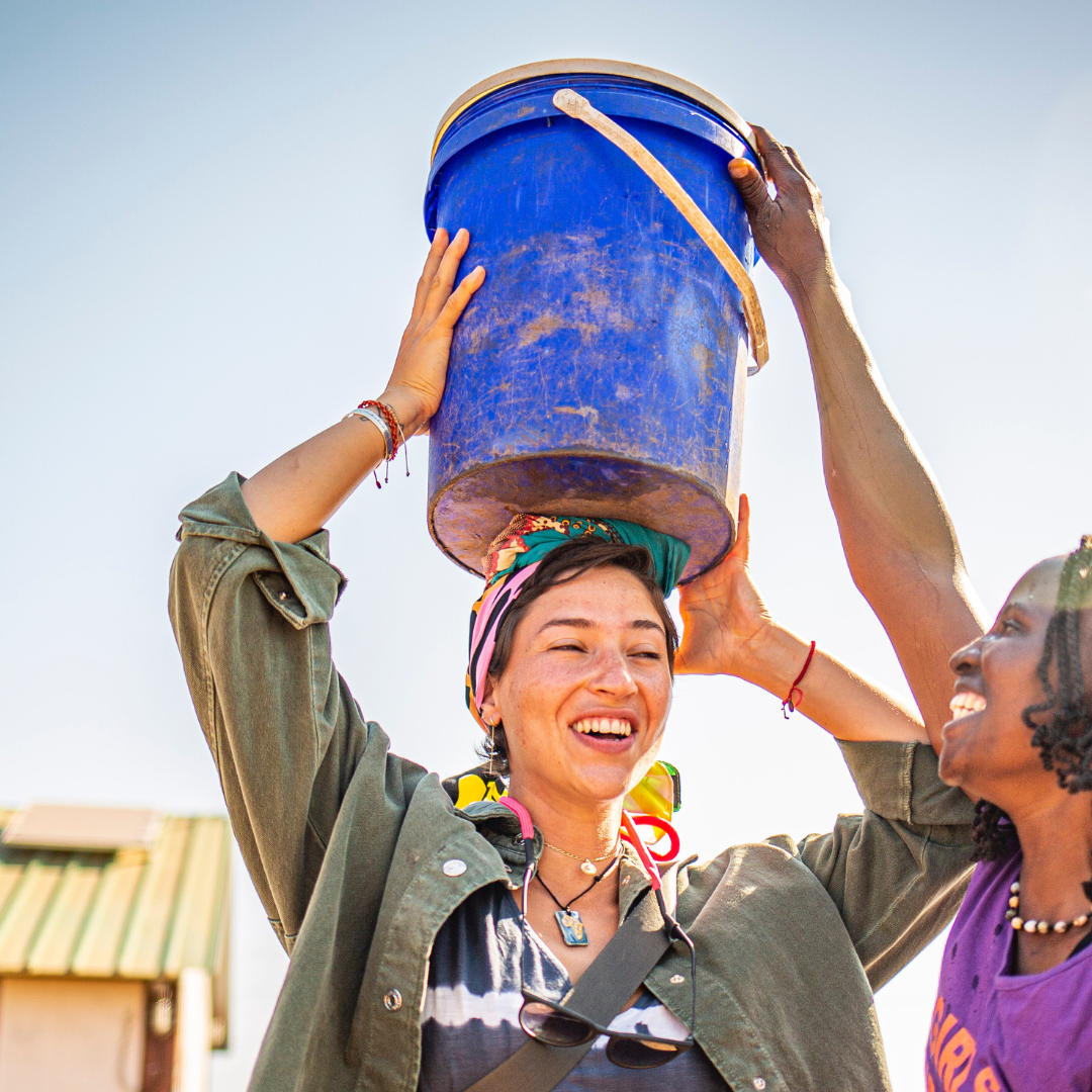 volunteering carrying a bucket on her head during a village tour in Livingstone Zambia