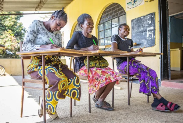 Three women seated at desks during adult literacy class.