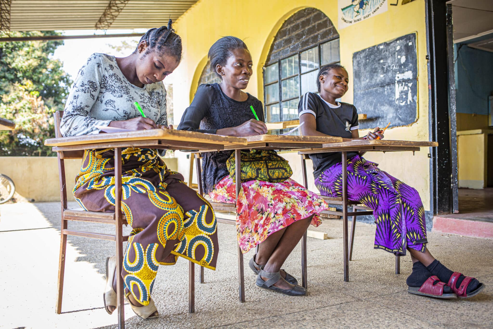 Three women seated at desks during adult literacy class.