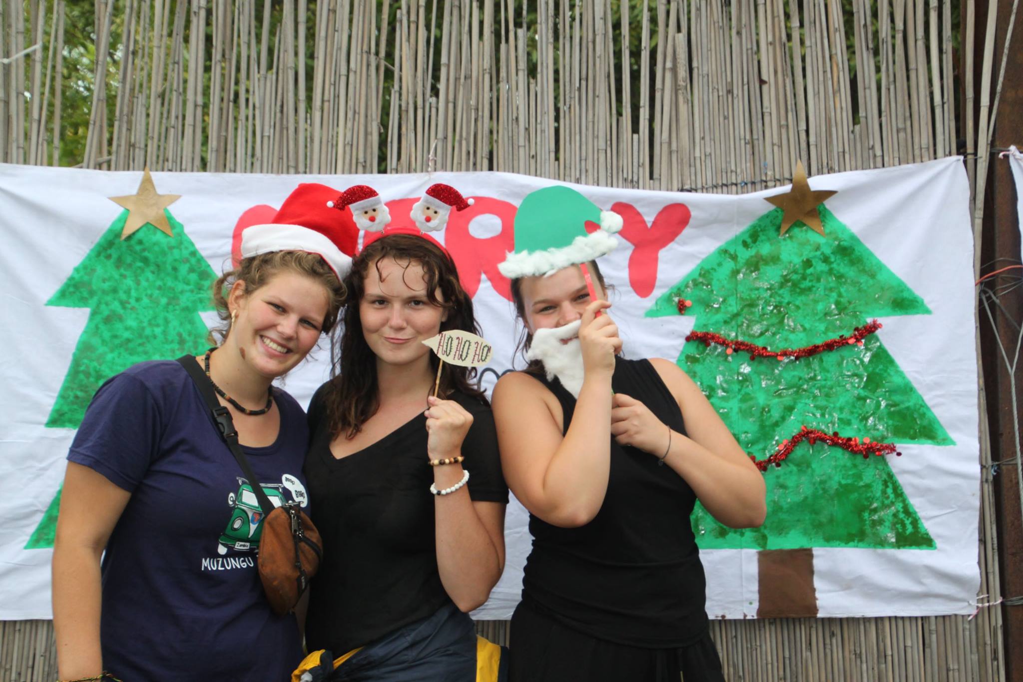 Three volunteers smiling for a photo together in Christmas outfits