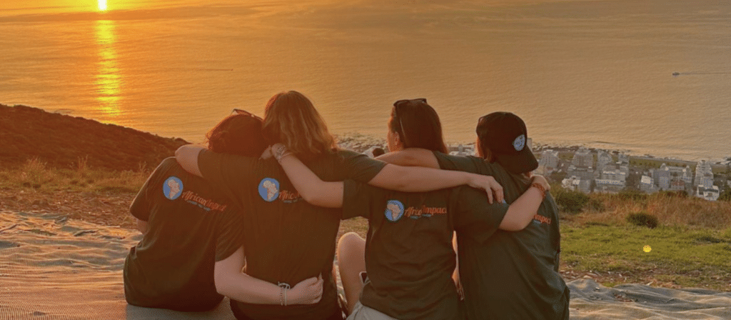 volunteers sitting near a sea while watching the sunset