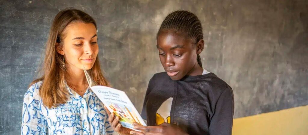 a teacher looking at a booklet her student is holding
