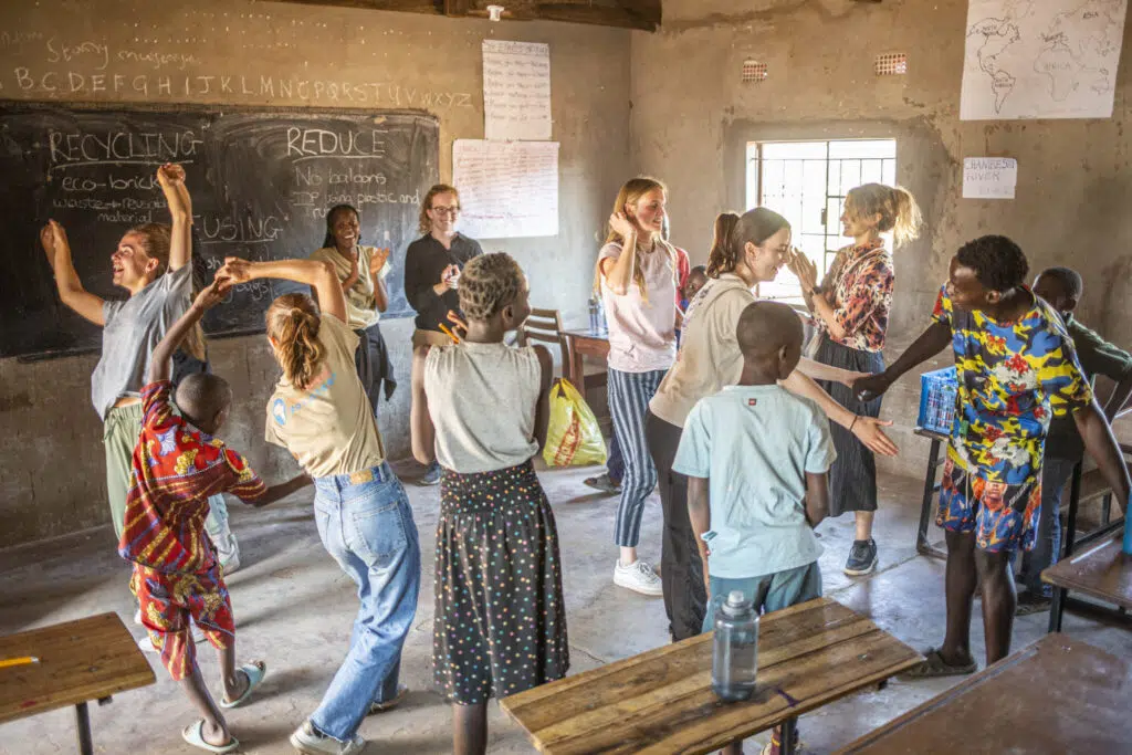 volunteers and children dancing inside a classroom