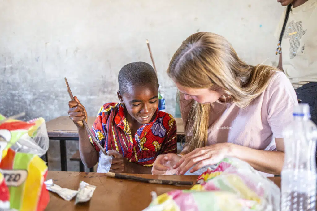 a volunteer and a young boy making crafts together