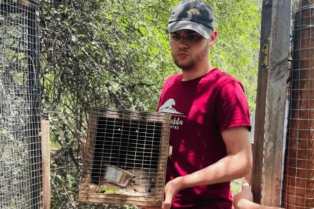 a man holding a bird in a cage