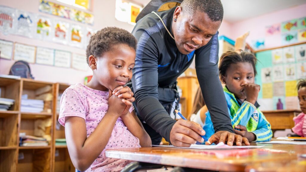 a man teaching a young girl while writing on a paper