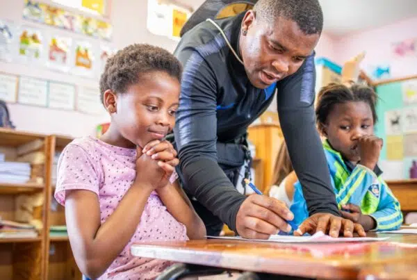 a man teaching a young girl while writing on a paper