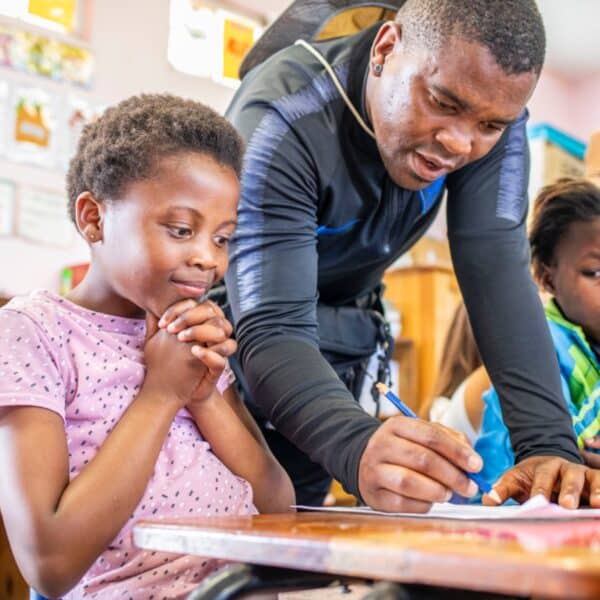 a man teaching a young girl while writing on a paper