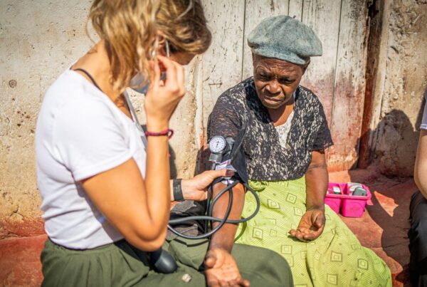 a healthcare volunteer checking a woman's blood pressure