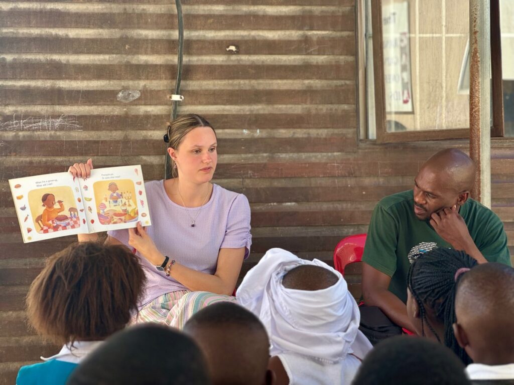 Volunteer showing and reading a book to children