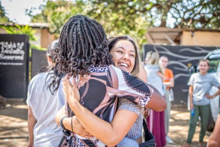 Two women warmly embracing outdoors, sharing a joyful moment
