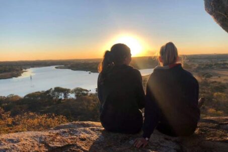 Two women sitting side by side, enjoying the sunrise view