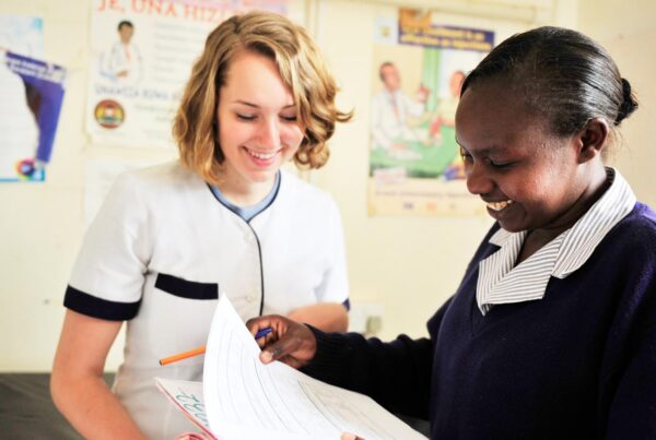 a volunteer and a local healthworker checking a medical chart