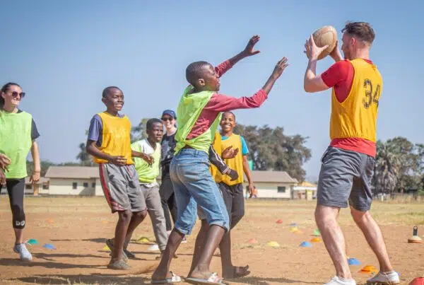 children and volunteers playing football on the field